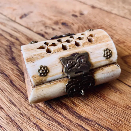 Scatola decorativa in legno con chiusura in metallo e fori intagliati sulla parte superiore.