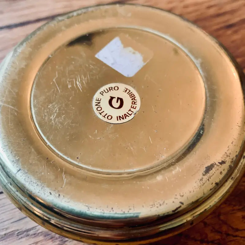 Coperchio metallico di un barattolo con un’etichetta circolare al centro.