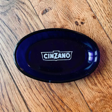 Piatto ovale blu scuro con logo Cinzano stampato in bianco.