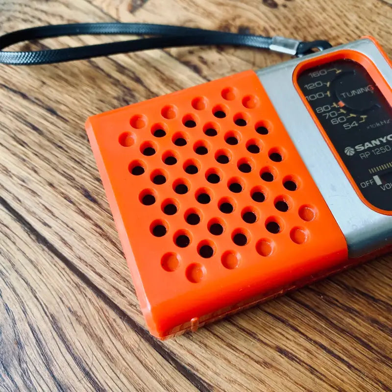 Radio portatile arancione e argento con griglia dell’altoparlante perforata.