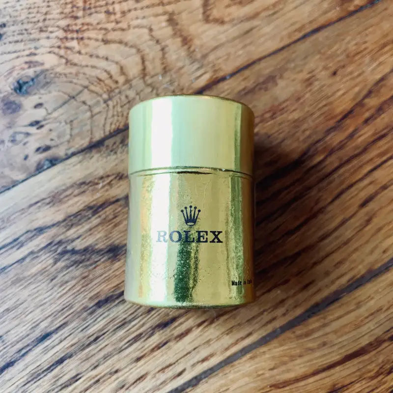 Contenitore cilindrico color oro con logo Rolex.