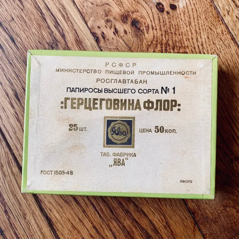 Pacchetto di sigarette d’epoca sovietica con l’etichetta ’Герцеговина Флор’ (Herzegovina Flor) su una superficie di legno.