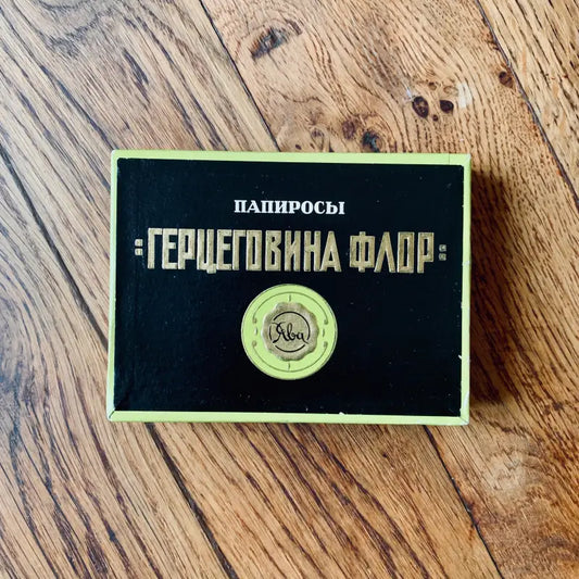 Pacchetto di sigarette russo vintage con testo verde e oro su sfondo nero.