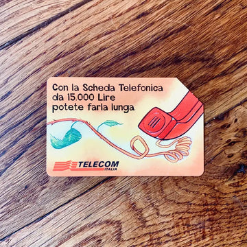Scheda telefonica italiana d’epoca di Telecom Italia con un’illustrazione a fumetti di una cornetta telefonica rossa.