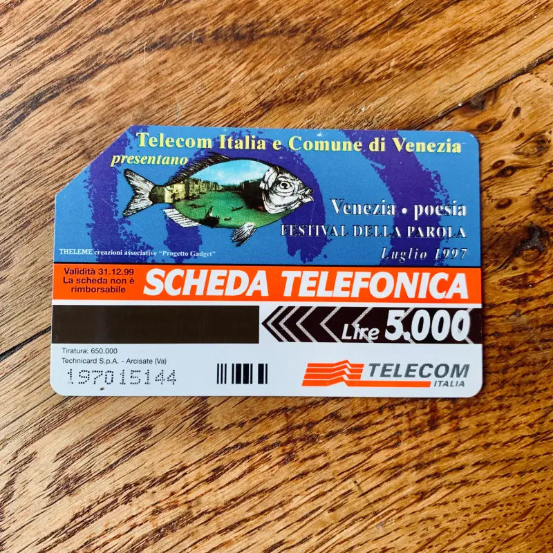 Scheda telefonica italiana con il disegno di un pesce colorato e un testo su Venezia.