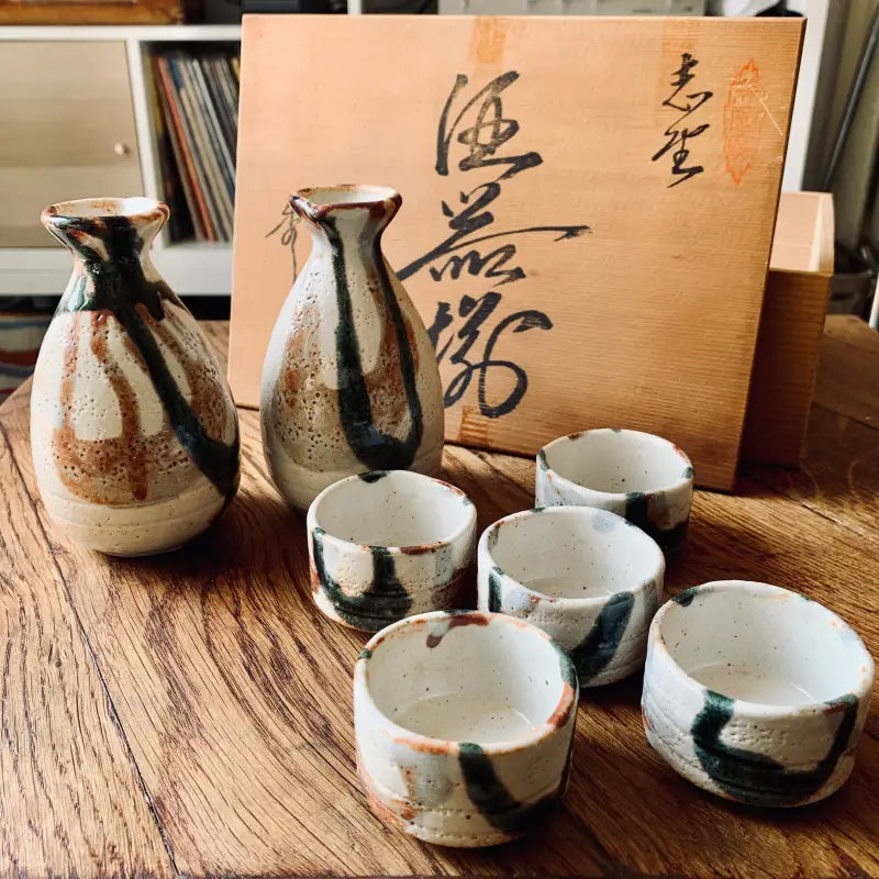 Set da sakè giapponese con bottiglie e tazze in ceramica e tavoletta per calligrafia.