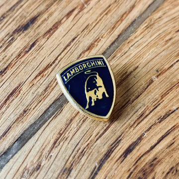 Stemma con logo Lamborghini su una superficie di legno.