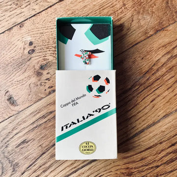 Spilla o distintivo commemorativo della Coppa del Mondo FIFA Italia ’90 in una scatola verde e bianca.