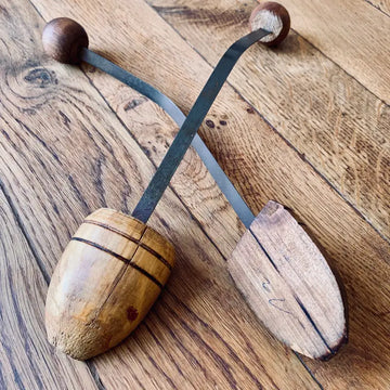 Strumento a percussione in legno con due pezzi a forma di uovo su cinghie di cuoio.