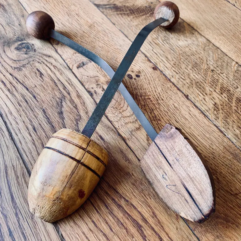 Strumento a percussione in legno con due pezzi a forma di uovo su cinghie di cuoio.