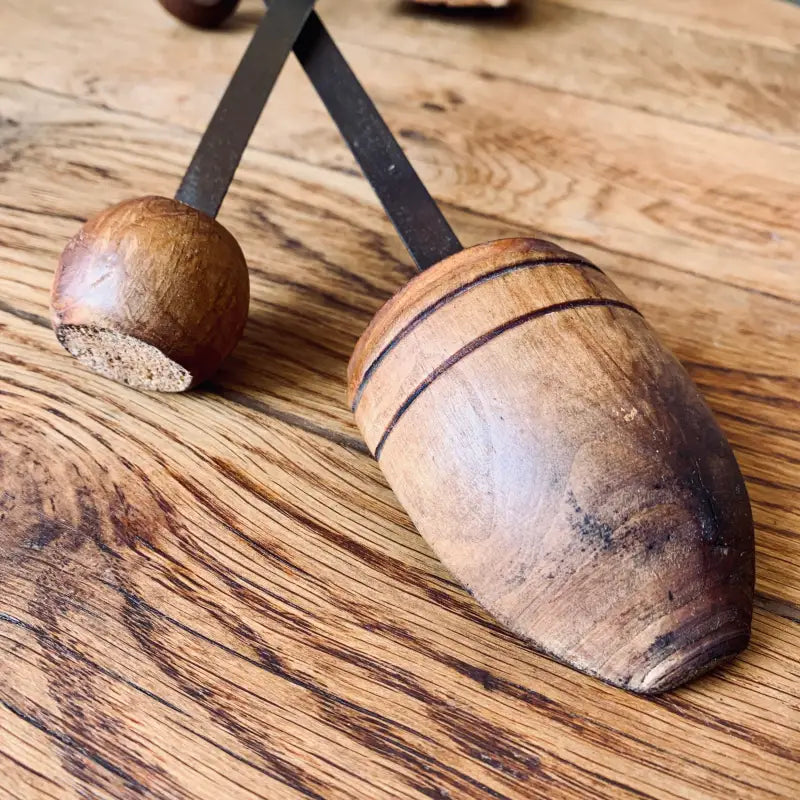 Strumento a percussione in legno simile a un piccolo mazzuolo o martello con testa arrotondata e corpo allungato.